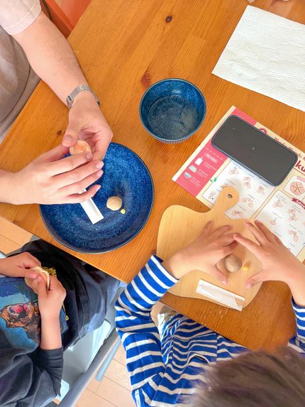 A mother and child preparing soft dough together at a kitchen table